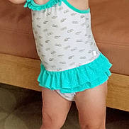 Romy participe au concours pour gagner de l'argent avec cette photo : toddler, child, swimsuit, playful, smiling, indoor, couch, floor, tile, footwear, sandals, hair_tie, happy, person, cute, standing, clothing, legs, face, pose