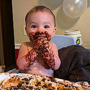 Beau is registered to the contest to win money with this photo: baby, child, messy, chocolate, food, happy, smiling, hands, face, table, highchair, indoor, balloons, birthday, celebration, cute, dirt, fun, eating, joy