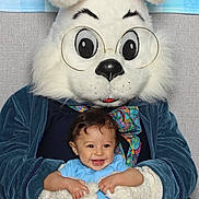 Liam is registered to the contest to win money with this photo: baby, child, costume, bunny, glasses, smile, person, indoor, plush, blue_shirt, shorts, floral_frame, purple, digital_overlay, weather_widget, year_2026, portrait, holiday, cute, celebration