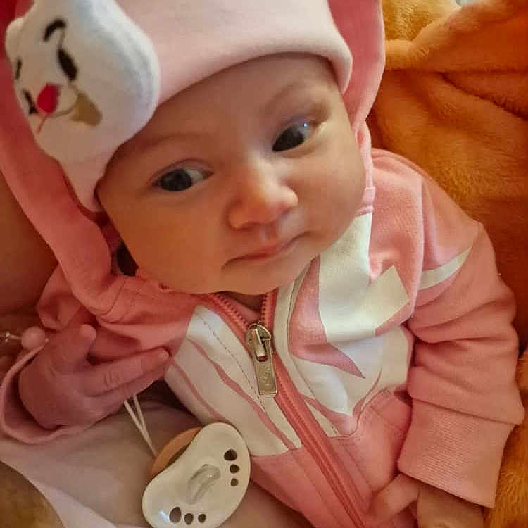 Larine a rejoint le concours — aidez-le/la à gagner de superbes lots ! baby, blanket, casual, child, cozy, cute, expression, face, hat, hoodie, indoors, infant, lying_down, newborn, pacifier, pink_clothing, relaxed, small_hands, soft_toys, warm_clothing