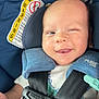 baby, blue, car_seat, child, closeup, clothing, cute, fabric, happy, indoors, infant, person, portrait, safety_harness, seat, seatbelt, smiling, tongue_out, warning_label, winking