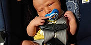 Dean is registered to the contest to win money with this photo: baby, car_seat, pacifier, infant, child, seatbelt, yellow_clothing, barefoot, indoors, human, young_child, safety_harness, cute, relaxed, skin, head, legs, feet, hand, face
