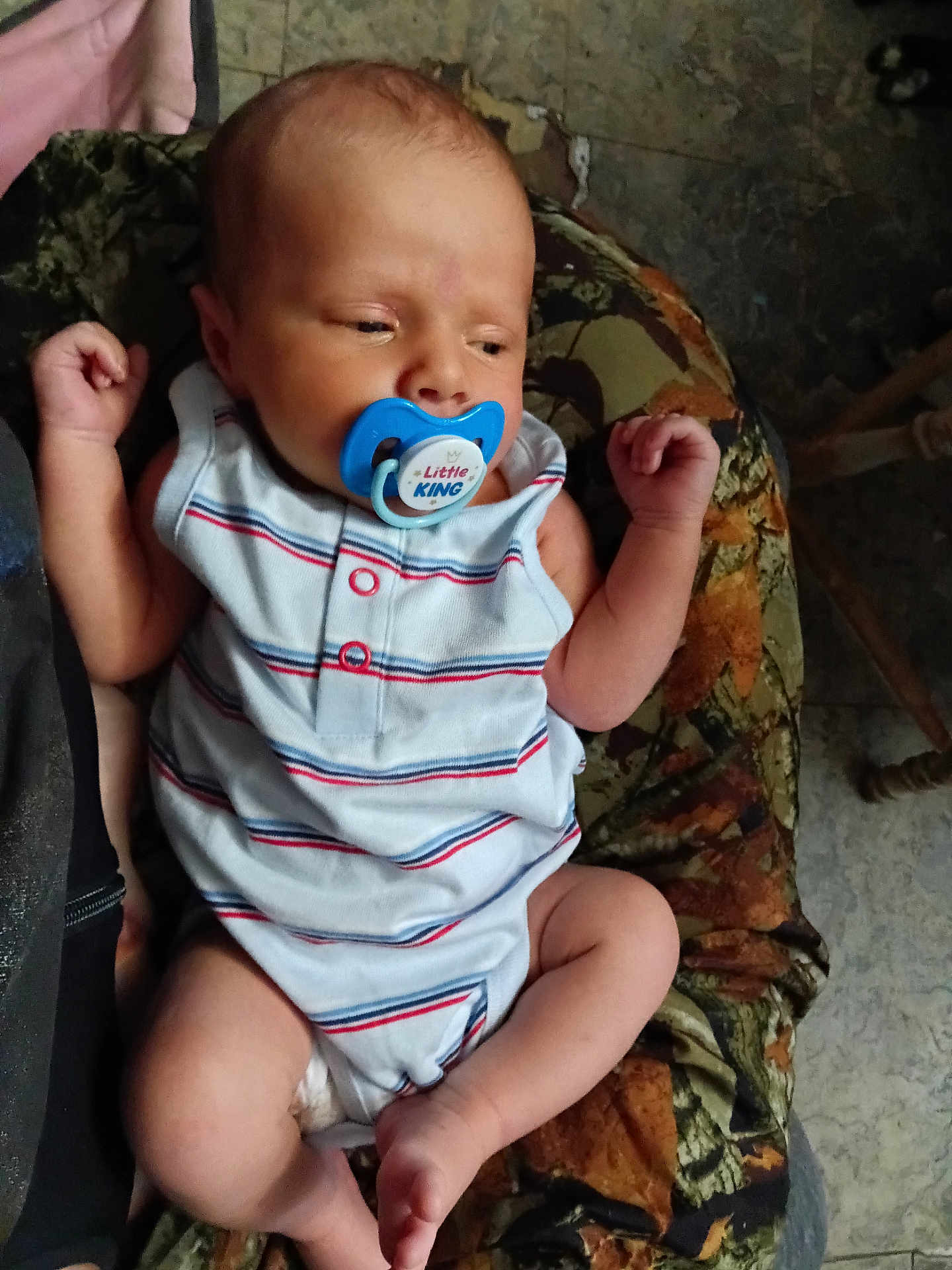 Dean is registered to the contest to win money with this photo: baby, infant, pacifier, onesie, striped_clothing, cushion, patterned_fabric, resting, sleepy, small_hands, small_feet, indoor, person, child, newborn, cute, relaxed, face, head, closeup