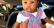Davina joined the competition — help win amazing prizes! toddler, child, baby, plaid_dress, red_bows, toy, hand, watch, car, black_car, outdoor, person, face, curly_hair, earrings, white_shirt, holding, expression, portrait, floor