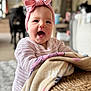 baby, child, smiling, headband, pink, blanket, woven_basket, indoor, person, happy, cute, face, sweater, home, dog, blurred_background, infant, cozy, portrait, expression