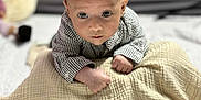 Isaac participe au concours pour gagner de l'argent avec cette photo : baby, infant, child, blanket, striped_shirt, face, head, eyes, skin, hands, crawling, indoor, soft_texture, bedspread, curious, portrait, young, person, cute, focused