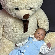 Isaac a rejoint le concours — aidez-le/la à gagner de superbes lots ! baby, teddy_bear, plush_toy, blue_outfit, white_shirt, infant, soft_texture, couch, indoor, child, cute, portrait, relaxed, small_hand, buttoned_clothing, light_blue, brown_nose, stuffed_animal, cozy, young_child