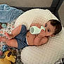 baby, blanket, blue_toy, bottle, child, curious, cushion, face, foot, hand, indoor, infant, lion_toy, pillow, playpen, relaxed, sitting, sleepwear, stuffed_animal, toy
