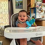 baby, carpet, celery, child, clothing, curtain, face, furniture, happy, high_chair, indoor, kitchen, magnet, person, photo, refrigerator, shelf, smiling, teething_toy, trophy
