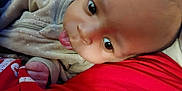 Wyatt is registered to the contest to win money with this photo: baby, infant, face, tongue, clothing, beige_outfit, red_fabric, close_up, skin, person, cute, sleepwear, newborn, child, expression, tongue_out, resting, indoor, soft_texture, young