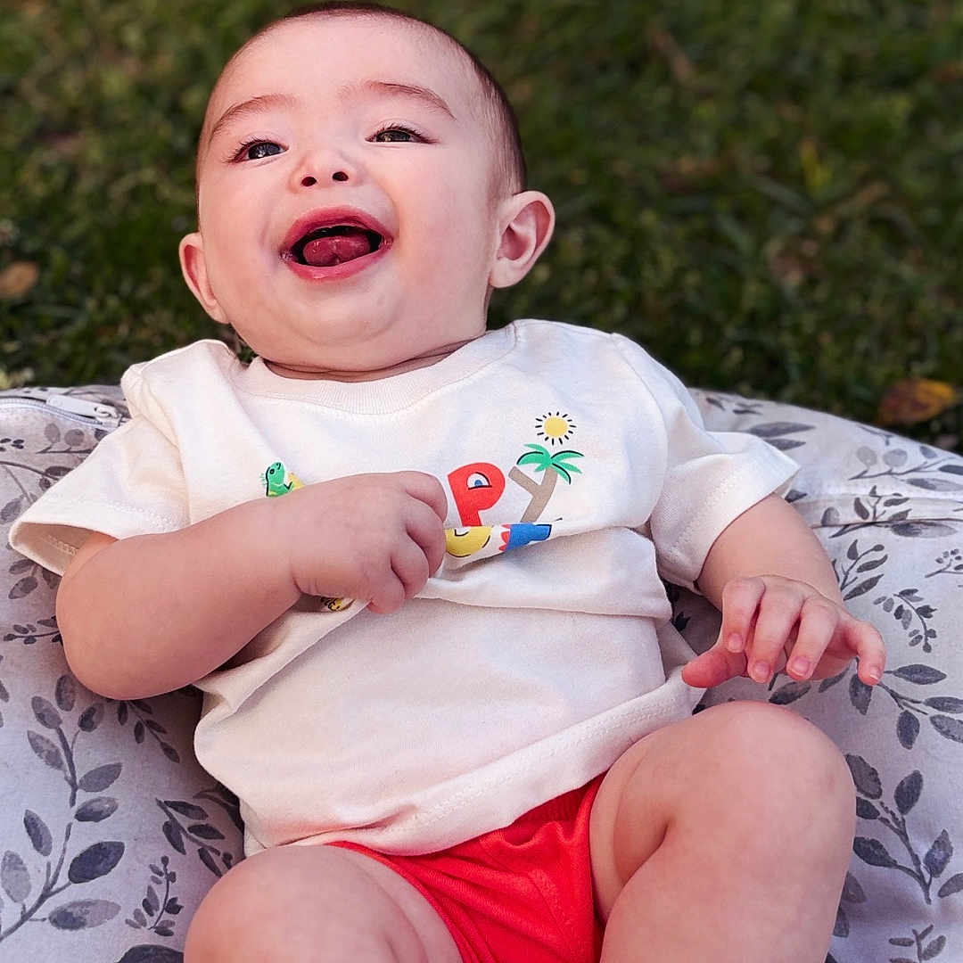 Tabias joined the competition — help win amazing prizes! baby, babylaughing, bodypart, clothing, face, finger, grass, hand, happy, head, laughing, newborn, person, photography, plant, portrait, shorts, sitting, smile, t_shirt