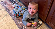 Huntley joined the competition — help win amazing prizes! toddler, child, smiling, pajamas, toy, floor, kitchen, mat, cabinet, wooden_cabinet, tile_floor, indoor, happy, person, young_child, playful, cute, home, portrait, lying_down