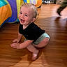 Huntley is registered to the contest to win money with this photo: toddler, child, crawling, smiling, indoor, wooden_floor, play_tent, colorful, happy, curly_hair, black_shirt, shorts, motion_blur, home, furniture, living_room, person, cute, playtime, floor