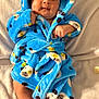 baby, infant, blue_robe, panda_print, blanket, soft_texture, cute, cozy, face, bare_feet, indoors, portrait, child, smiling, fuzzy_clothing, lying_down, warm, comfort, small_hands, adorable