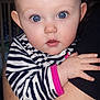 baby, child, blue_eyes, face, hand, striped_clothing, zebra_pattern, infant, person, portrait, cute, closeup, skin, eyelashes, pink_trim, holding, expression, indoor, adult_arm, curious
