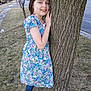 child, girl, tree, floral_dress, smile, outdoor, sidewalk, grass, street, bare_trees, spring, nature, footwear, blue_tights, gold_shoes, young, portrait, casual, daytime, happy