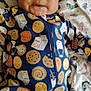 baby, child, infant, onesie, cookie_pattern, milk_carton_pattern, blanket, face, smile, cute, indoor, lying_down, clothing, curly_hair, soft_toys, portrait, young_child, sleepwear, comfort, playful