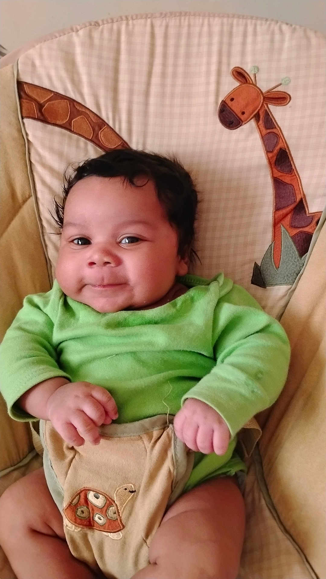 Ja'Kariyon joined the competition — help win amazing prizes! baby, infant, child, green_clothing, smiling, face, hands, legs, cushion, baby_chair, giraffe_pattern, turtle_patch, cute, indoors, portrait, seated, soft_fabric, plush, comfortable, happy