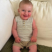Gaspard participe au concours pour gagner de l'argent avec cette photo : baby, child, smiling, sitting, couch, beige, striped_shirt, khaki_shorts, happy, face, skin, indoors, casual_clothing, infant, cute, portrait, young_child, furniture, relaxed, comfort