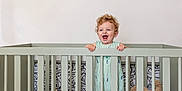 Bennett joined the competition — help win amazing prizes! baby, banner, bed, blanket, child, crib, curly_hair, furniture, happy, home, interior, nursery, pattern, person, plush, room, smile, standing, toddler, toy