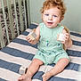 Bennett is registered to the contest to win money with this photo: baby, bed, blue_eyes, child, crib, curly_hair, cute, furniture, happy, indoor, infant, person, play, quilt, room, sitting, smiling, striped_clothing, toddler, wooden_blocks