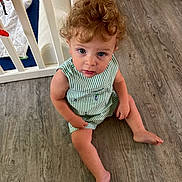 Bennett is registered to the contest to win money with this photo: baby, barefoot, casual_clothing, child, crib, curious, curly_hair, cute, floor, green_and_white, home, indoor, infant, looking_up, portrait, sitting, striped_clothing, toddler, wood_floor, young_child