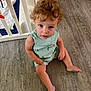 baby, barefoot, casual_clothing, child, crib, curious, curly_hair, cute, floor, green_and_white, home, indoor, infant, looking_up, portrait, sitting, striped_clothing, toddler, wood_floor, young_child