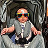 Dominic is registered to the contest to win money with this photo: baby, stroller, sunglasses, price_tag, infant, child, seatbelt, clothing, hands, cute, fashion, accessory, portrait, casual, indoor, person, kid, seat, baby_boy, colorful