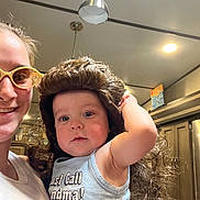 Dominic joined the competition — help win amazing prizes! child, toddler, adult, person, wig, glasses, indoor, kitchen, smile, shirt, text, lighting, cabinet, ceiling_light, curly_hair, funny, portrait, holding, family, casual