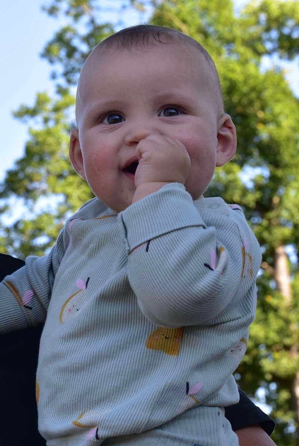 Thélyo a rejoint le concours — aidez-le/la à gagner de superbes lots ! baby, child, smiling, face, hand, onesie, clothing, outdoor, trees, greenery, blue_sky, person, cute, happy, young, infant, nature, daylight, portrait, playful