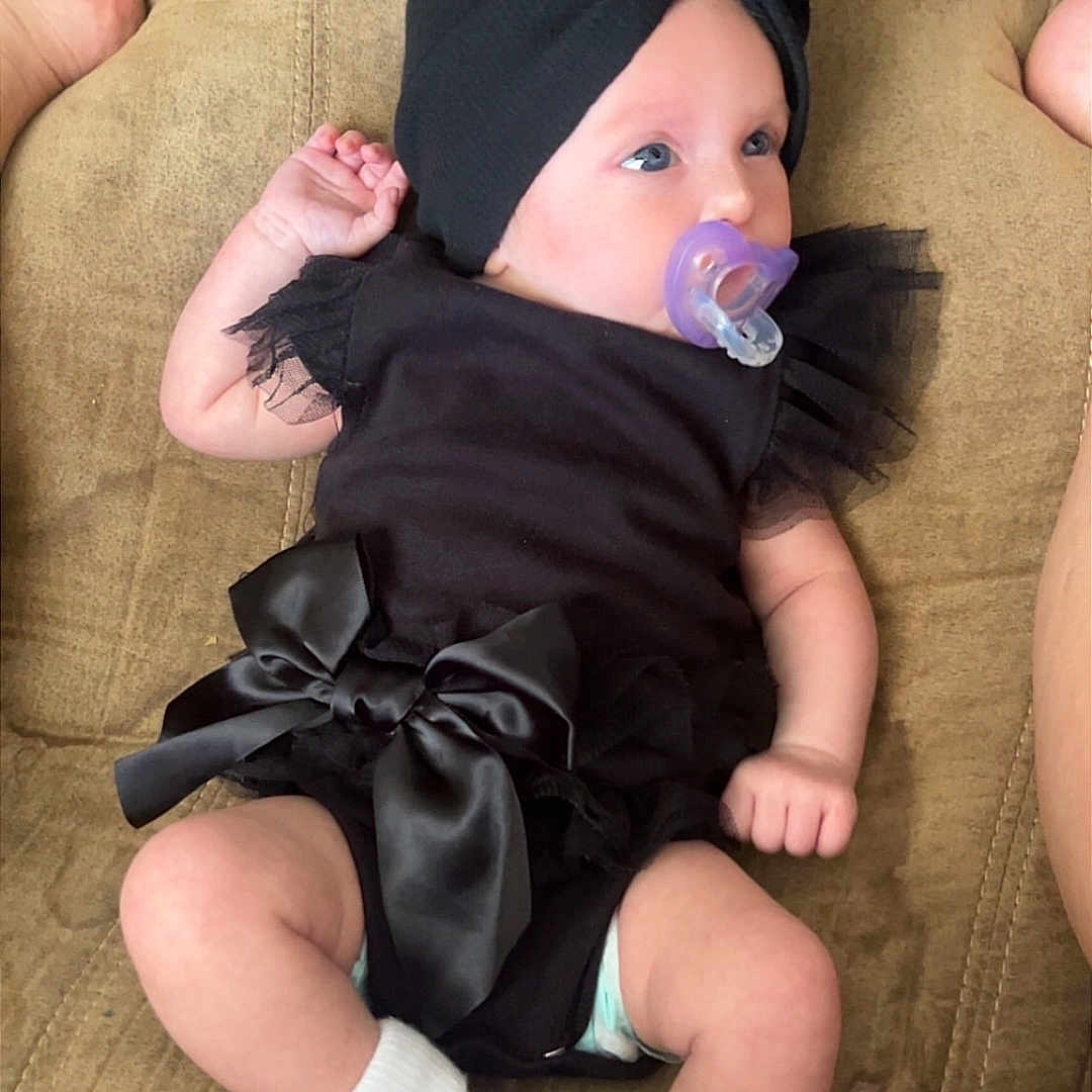 Willow Melson joined the competition — help win amazing prizes! baby, black_outfit, bow, child, cloth, couch, cute, feet, flower_socks, headwear, indoor, infant, legs, pacifier, pacifier_clip, person, relaxing, socks, soft_fabric, toddler
