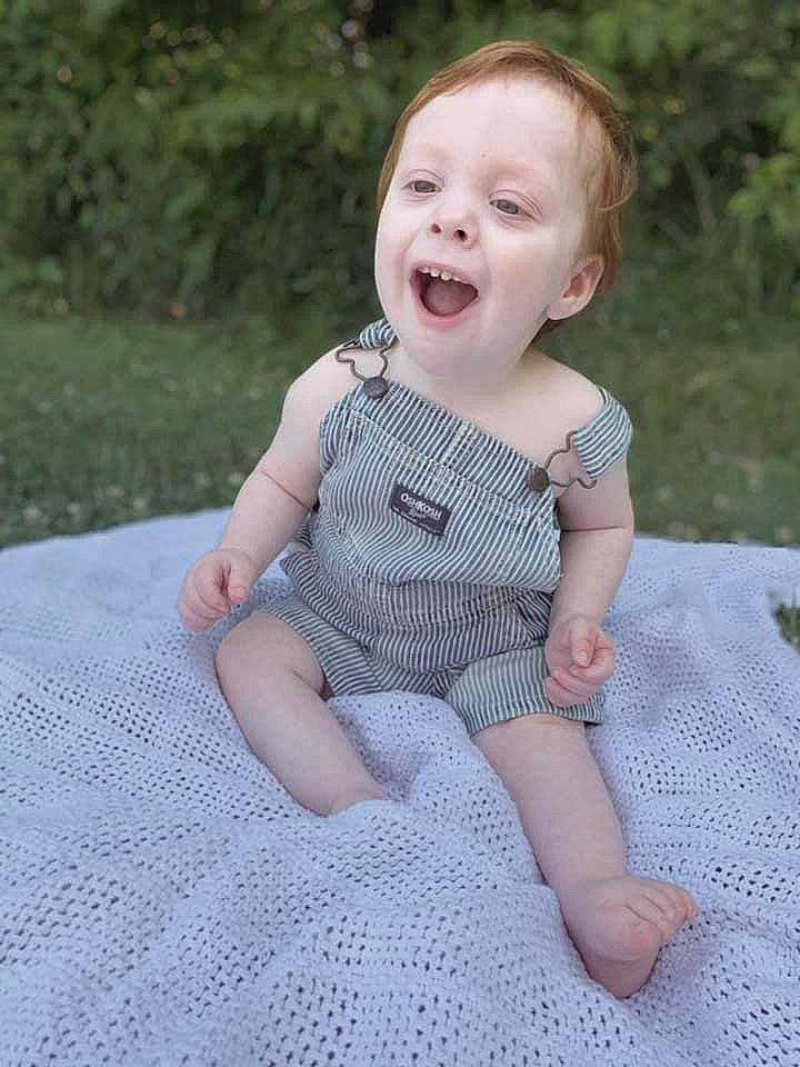Cameron is registered to the contest to win money with this photo: art, baby, baby_toddler_clothing, child, day_dress, face, fun, grass, happy, head, iris, lip, pattern, person, plant, sitting, skin, sleeve, smile, toddler