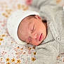 baby, newborn, sleeping, hat, knitwear, blanket, floral_pattern, peaceful, infant, cute, soft, portrait, child, resting, closeup, cozy, indoors, skin, hand, face