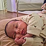 baby, sleeping, pajamas, infant, cozy, bed, indoor, peaceful, soft, home_decor, plant, blurred_background, furniture, child, cute, rest, portrait, relaxation, newborn, comfort