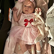 Ava is registered to the contest to win money with this photo: baby, infant, pink_clothing, headband, bow, plush_toy, blanket, sock, tutu, onesie, lying_down, soft_toy, cute, indoors, child, newborn, person, baby_girl, resting, portrait