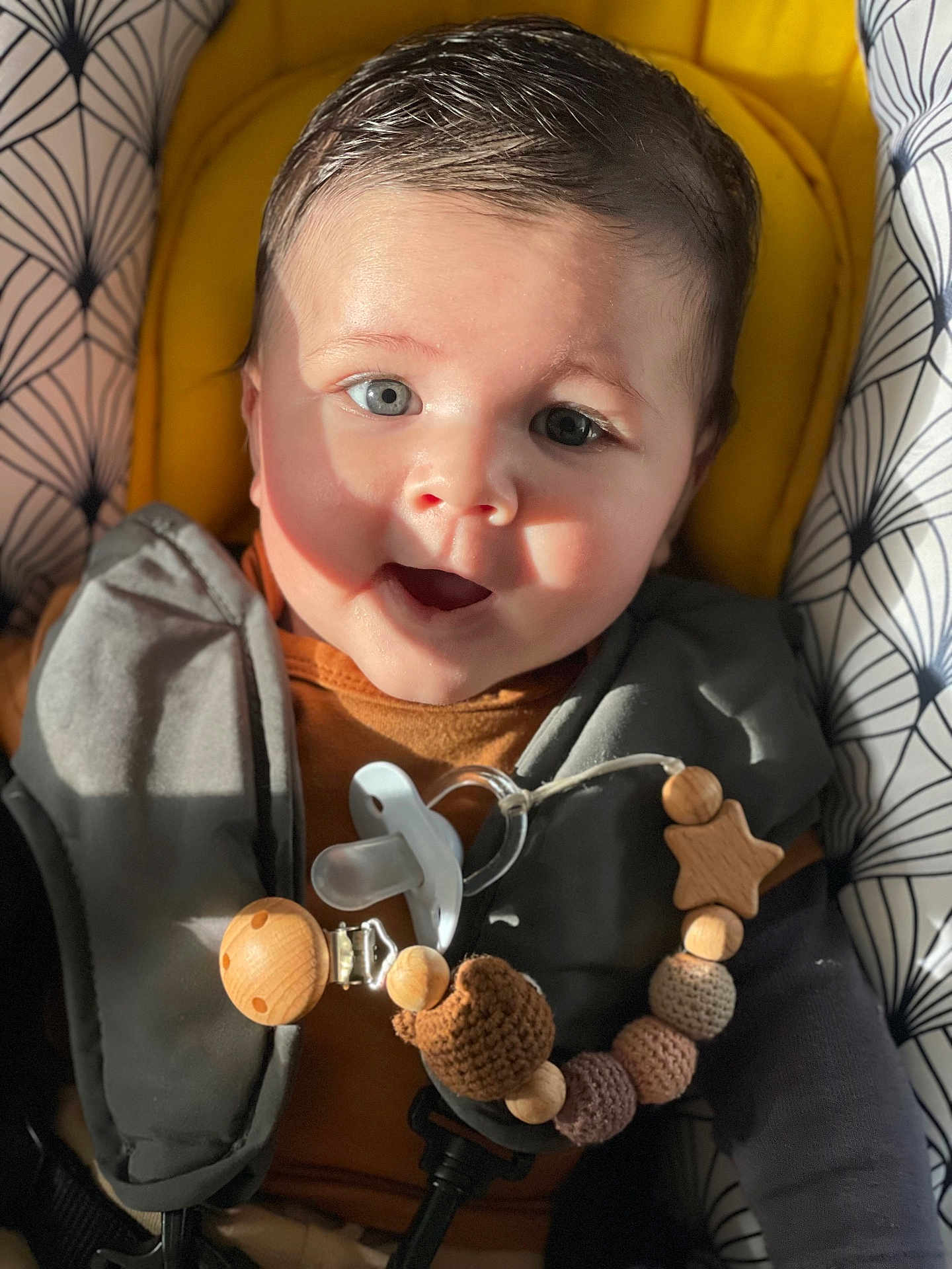Milo participe au concours pour gagner de l'argent avec cette photo : baby, infant, smile, face, pacifier, toy, seat, sunlight, patterned, clothing, cute, child, portrait, indoor, happy, wooden_beads, star_shaped_toy, closeup, young, expression