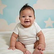Samona is registered to the contest to win money with this photo: baby, infant, smiling, sitting, white_clothing, blanket, fluffy, cute, happy, portrait, indoors, child, skin, face, hand, foot, star_pattern, cloud_pattern, background, soft