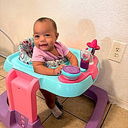 Justice is registered to the contest to win money with this photo: baby, blue, child, face, floor, happy, home, indoor, outlet, person, pink, play, purple, seat, smile, socks, tile, toy, walker, wall