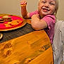toddler, child, smiling, blonde_hair, pink_shirt, sitting, table, wooden_table, plate, sandwich, chips, snack, happy, indoor, meal, food, face, person, dining, casual