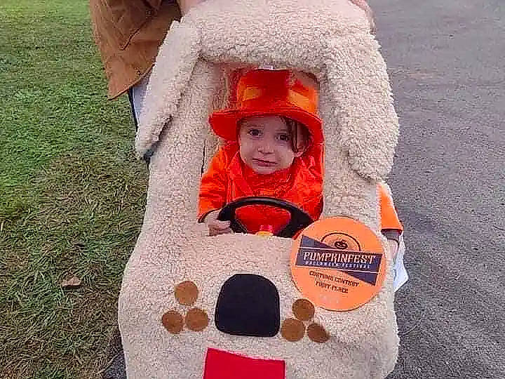 Gabriel is registered to the contest to win money with this photo: art, baby, baby_carriage, baby_products, baby_toddler_clothing, child, fashion_accessory, fun, grass, happy, hat, headgear, headwear, orange, pattern, person, sitting, sleeve, sun_hat, sunglasses
