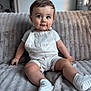baby, infant, child, couch, sofa, overalls, white_clothing, socks, indoor, soft_texture, cute, portrait, seated, smiling, person, home, furniture, looking_at_camera, short_hair, happy