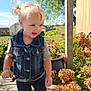 toddler, child, blonde_hair, denim_vest, pink_crocs, flower, porch, wooden_floor, plants, hydrangeas, sunny, outdoor, greenery, blue_sky, curious, casual_clothing, daylight, nature, playful, earrings