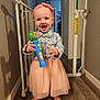 Arya joined the competition — help win amazing prizes! toddler, child, toy, microphone, headband, smile, barefoot, skirt, shirt, indoor, floor, wooden_floor, baby_gate, hallway, doorway, wall, shadow, earrings, person, happy