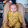 Sam participe au concours pour gagner de l'argent avec cette photo : baby, infant, yellow_onesie, legs, person, indoor, portrait, soft_focus, background_blur, television, cozy_clothing, cute, newborn, hands, face, eyes, sitting, relaxed, home, casual