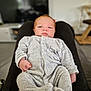 Sam participe au concours pour gagner de l'argent avec cette photo : baby, infant, onesie, clothing, person, legs, indoor, living_room, blurred_background, furniture, television, relaxed, cute, newborn, comfortable, portrait, human, soft_lighting, casual, home