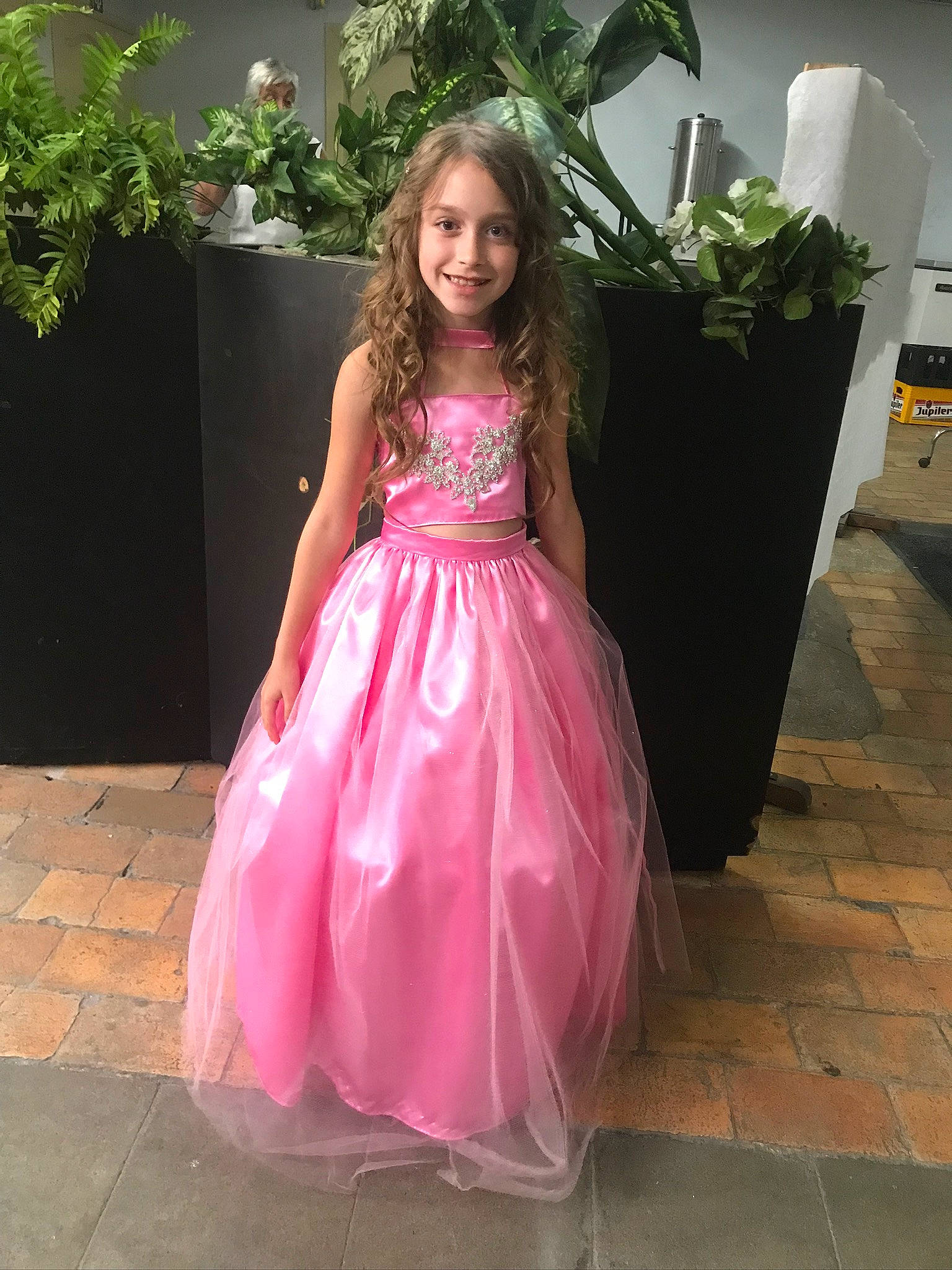 Iliana participe au concours pour gagner de l'argent avec cette photo : bridal_clothing, bridal_party_dress, day_dress, dress, embellishment, eye, face, fashion_design, flooring, formal_wear, gown, hairstyle, happy, joy, one_piece_garment, person, pink, plant, shoulder, smile