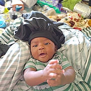 Adrian joined the competition — help win amazing prizes! baby, infant, clapping, bonnet, striped_clothing, bed, blanket, indoor, happy, cute, person, child, smiling, young, resting, fabric, soft, casual, playful, home