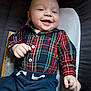 baby, buttoned_shirt, casual_wear, child, clothing, comfort, cushion, cute, face, hand, happy, indoors, infant, lying_down, navy_pants, person, plaid_shirt, portrait, smiling, young_child