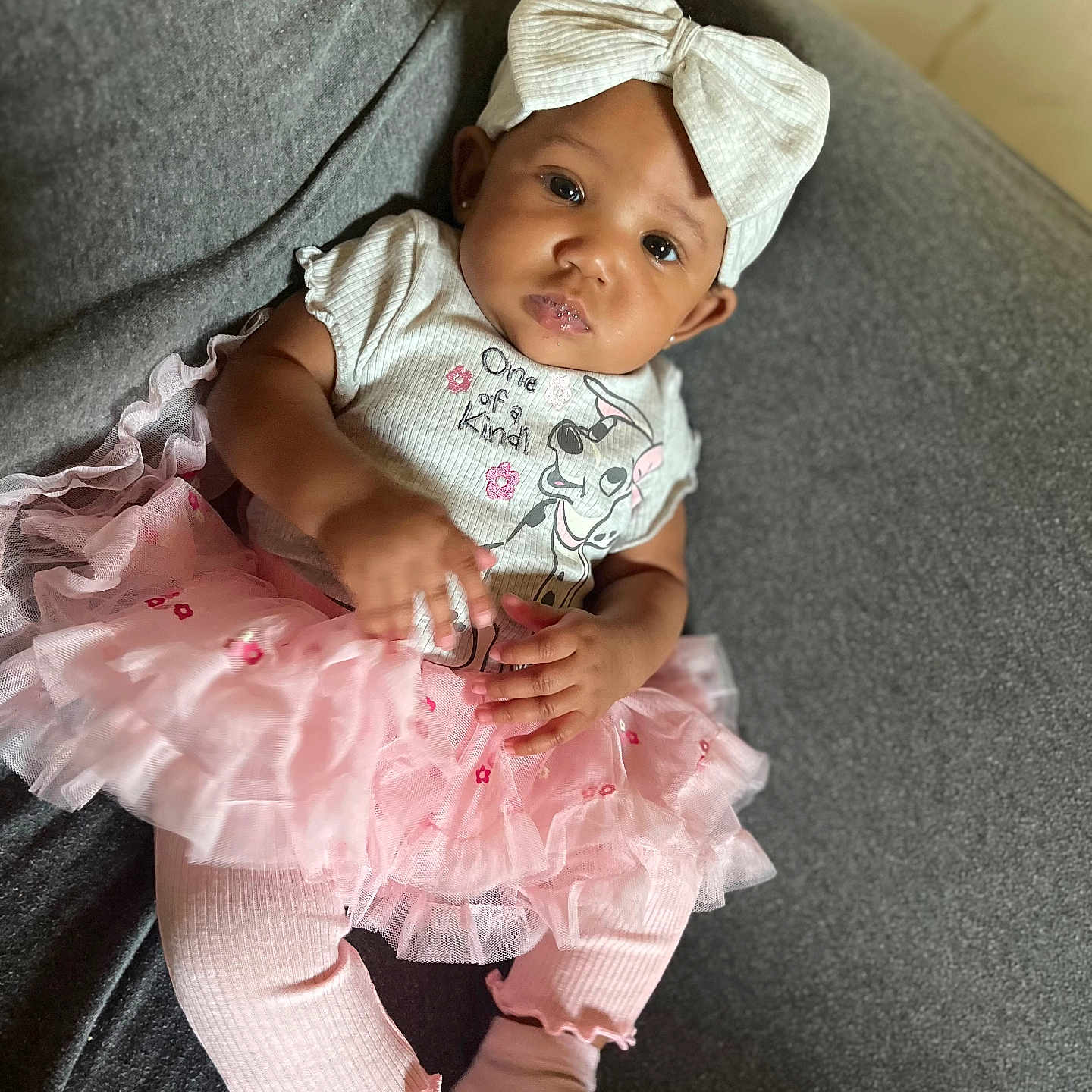 Kay Michelle joined the competition — help win amazing prizes! baby, child, clothing, couch, cute, fashion, gray_background, happy, headband, indoors, infant, leggings, person, pink_tutu, portrait, sitting, smiling, toddler, white_bow, young_child