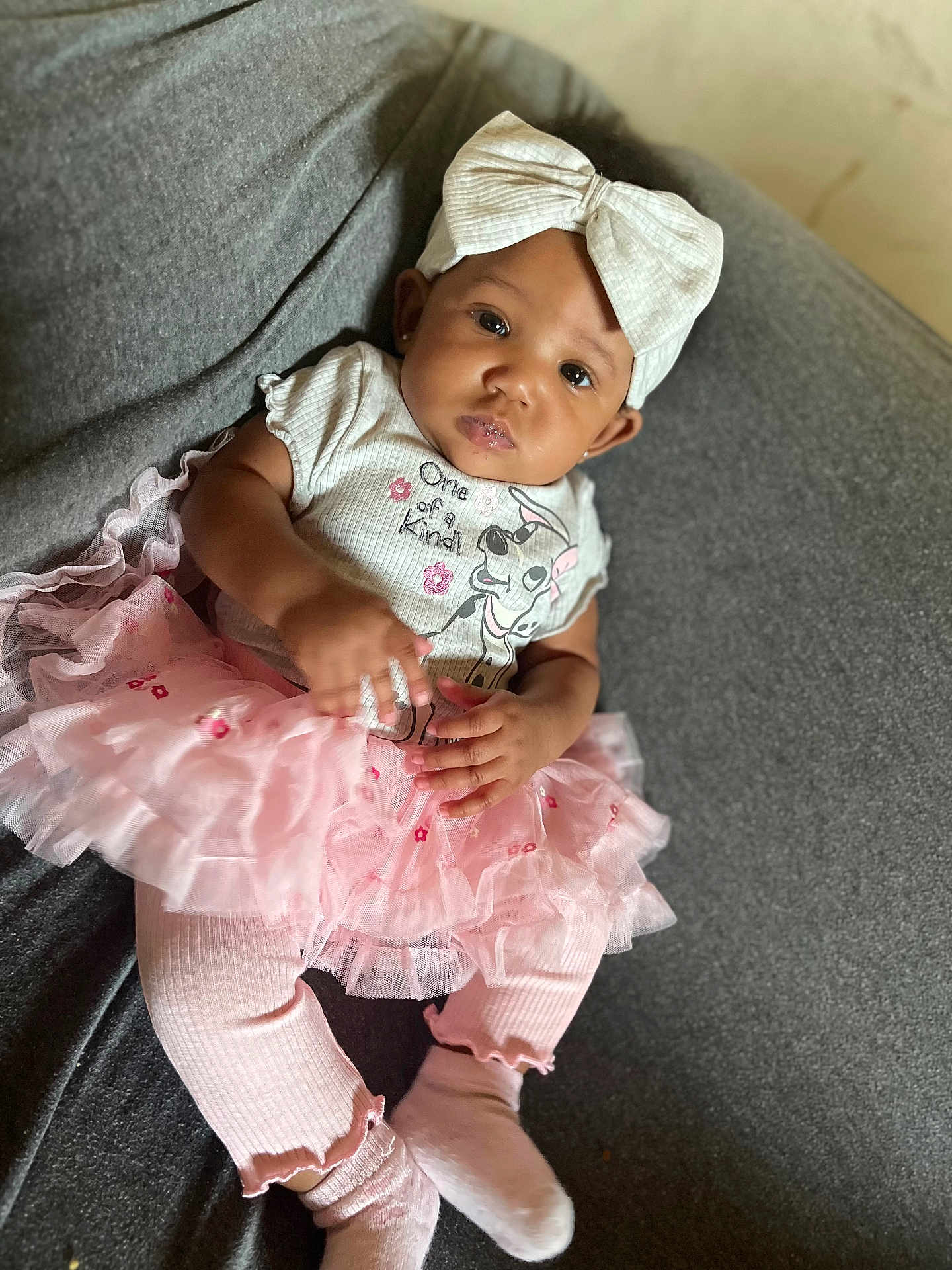 Kay Michelle joined the competition — help win amazing prizes! baby, child, clothing, couch, cute, fashion, gray_background, happy, headband, indoors, infant, leggings, person, pink_tutu, portrait, sitting, smiling, toddler, white_bow, young_child